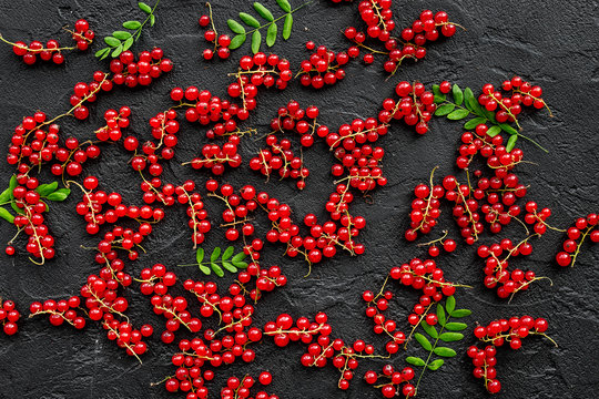 Berry theme. Red currant and leaves on black table background top view