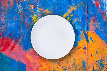 Top view of empty white plate put on colorful table with space for copy.