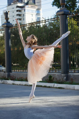 Young beautiful ballerina dancing outdoors in a park. Full length portrait.