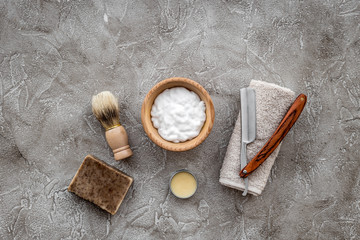 Fototapeta na wymiar Preparing for men shaving. Shaving brush, razor, foam on grey stone table background top view copyspace