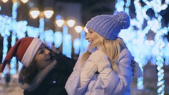 Young girl in santa's hat makes a suprise with a present for her friend