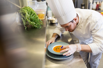 male chef decorating dish with pansy flower