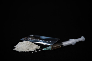 Drug syringe and cooked heroin isolated on black background