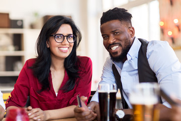 happy man and woman with smartphone at bar