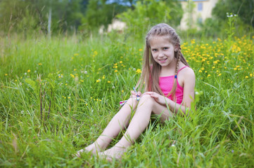 Fototapeta premium The girl is resting in the park sitting on green grass