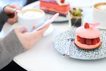 Girl Holding Phone Texting at the Cafeteria Drinking Coffee and Eating French Macaroon