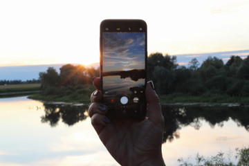 Female hands make a Photo sunset  using smartphone