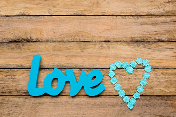 Love - blue turquoise wooden word with heart shape daisy ribbon on wooden background