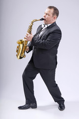 Fototapeta premium Playing the saxophone. Man. European. He plays the saxophone. Dressed in a suit.
