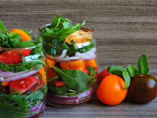 Salad with arugula and tomatoes in a jar. Fitness salad in the jar. Yellow black and pink tomatoes.