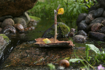 Handmade boat made from tree bark. Boats game in nature. Ship sailing in stream.