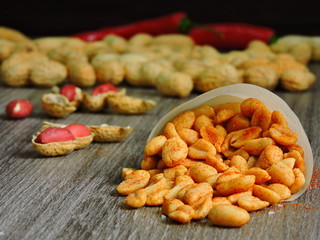 Delicious peanuts in a paper bag. Crude peanuts. Scarlet chili peppers. Close up.