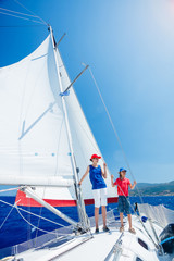 Boy with his sister on board of sailing yacht on summer cruise.