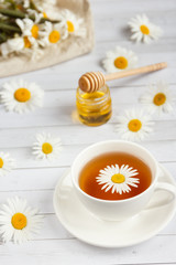 A Cup of chamomile tea and honey on white wooden background