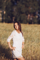 Portrait of a adorable young girl in a white dress on a background of field at sunset in the summer