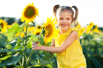 Little beautiful girl playing with a sunflower