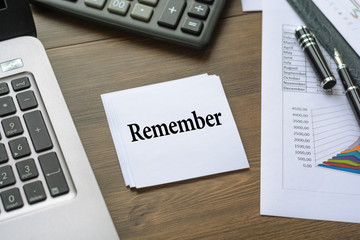 Sheet for inscriptions with text Remember on a table near a computer, a calculator, a fountain pen
