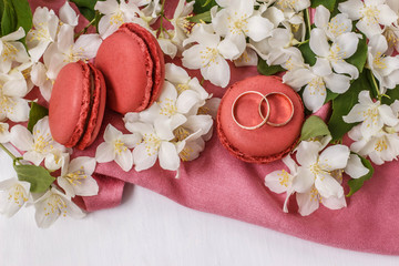 Golden wedding rings with flowers white Jasmine, macaroons and pink drape