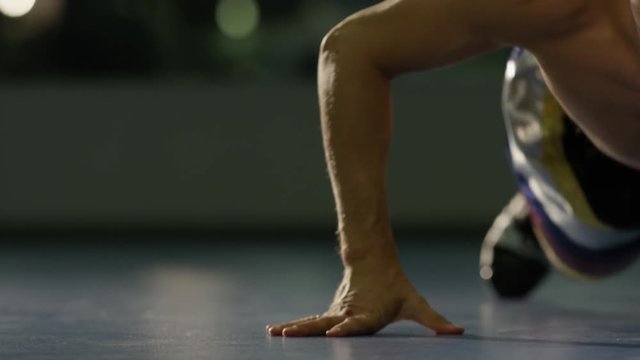 Young man workout in fitness club. Profile portrait of guy making plank or push ups exercise, training indoors. Side view of muscular man doing push up in gym. Side view of handsome sportsman doing