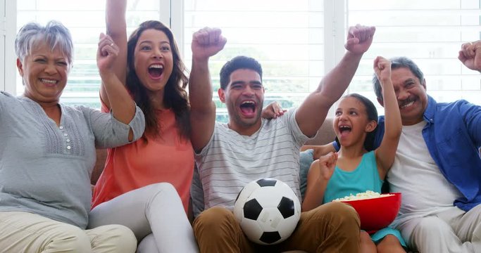 Family sitting on sofa and watching football match