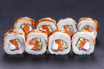 Delicious Golden Dragon sushi rolls with smoked eel, unagi sauce and sesame served on black stone table