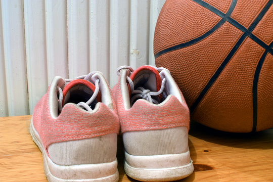 Sport shoes and basketball on wooden floor. Close up, square shape image.