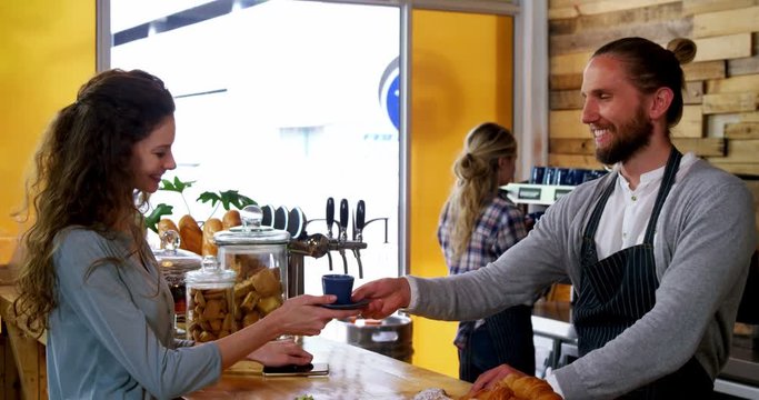 Waiter serving coffee to female costumer at counter