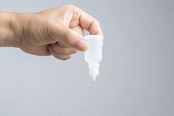Hand holding eye or ear drop bottle