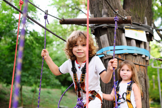 boy and a girl pass an obstacle course in a rope park
