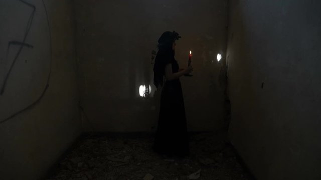 Demonic gothic evil woman turning around holding a candle and angrily screaming in a dark abandoned room