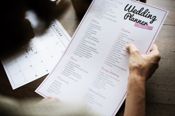 Fototapeta premium Hands Holding Wedding Planner Checklist Information Preparation