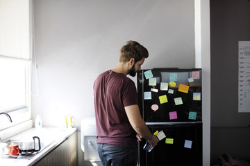 Man Taking Water Bottle From Fridge in Pantry Room During Break Time