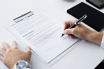 Closeup of hand signing paper workspace