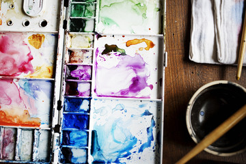 Closeup of paints and brushes artist tools on wooden table