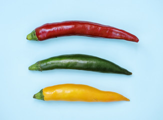 Aerial view of fresh red green yellow chili peppers on blue background