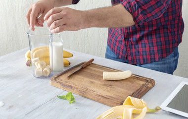 Man cooking tasty and healthy milkshake with a banana