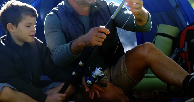 Father and son holding a fishing rod outside the tent