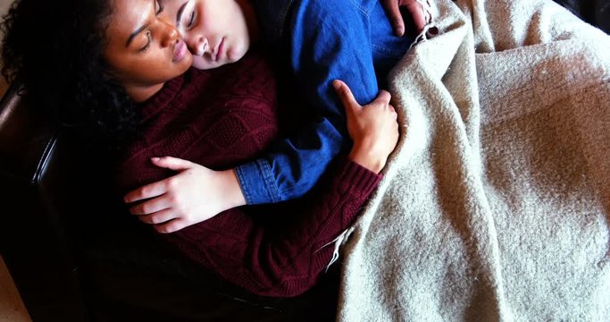 Lesbian couple sleeping together on couch