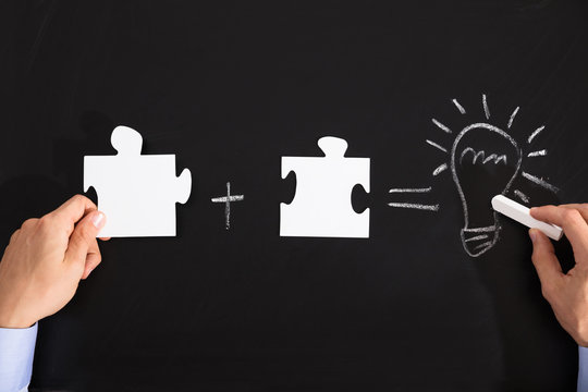 Person Drawing Idea Equation With White Puzzles