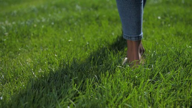 Close up of barefooted young girl walking on grass
