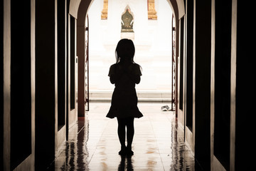 The silhouette of a girl standing pay respect in a temple
