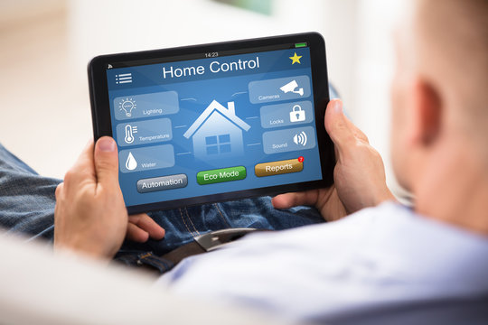 Man Using Home Control System On Digital Tablet