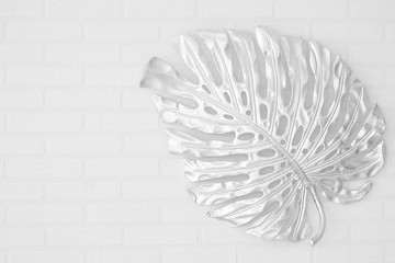 Shiny silver leaf on a white brick wall background