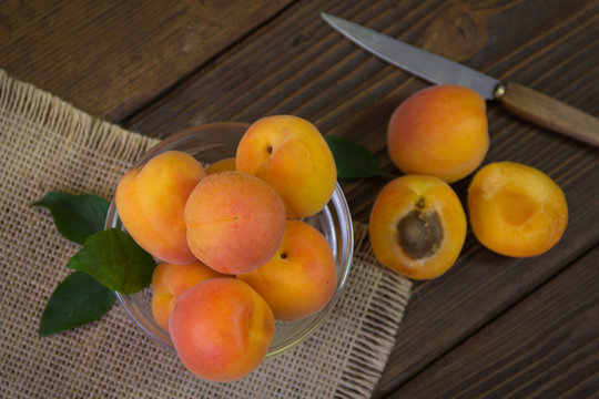 Freshly organic whole and halved apricots in a bowl on a wooden table