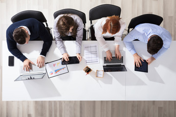 Business People Using Electronic Devices At Desk