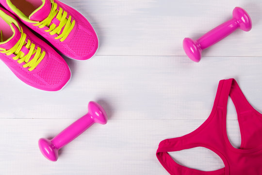 Women's sportswear, with pink dumbbells, on a light wooden floor