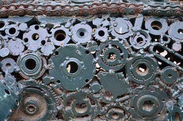 A composition of a set of gears and car parts that are welded to each other and painted green. Grunge steampunk texture