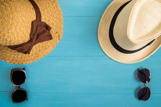 Travel Concept : Flat lay of Men and Women straw hats and sunglasses, on blue wooden background.