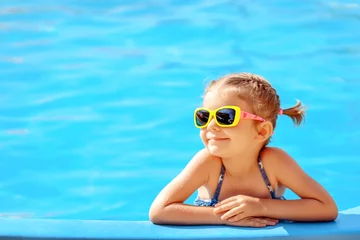Fotobehang Smiling cute little girl in sunglasses in pool in sunny day. © zamuruev