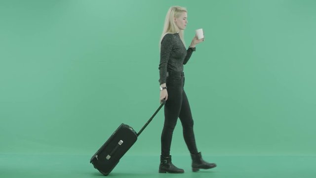 young blonde woman walking with luggage and coffee